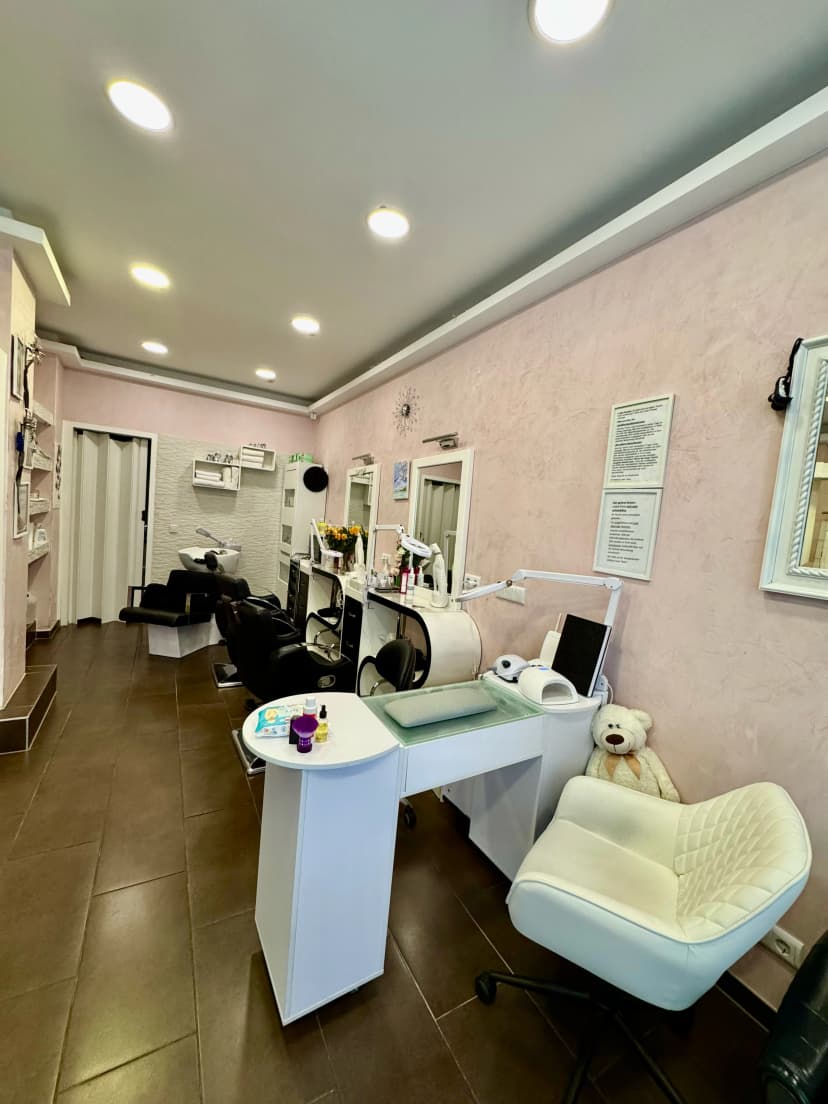 Nail and hair styling area with workstations and comfortable chairs in a bright setting