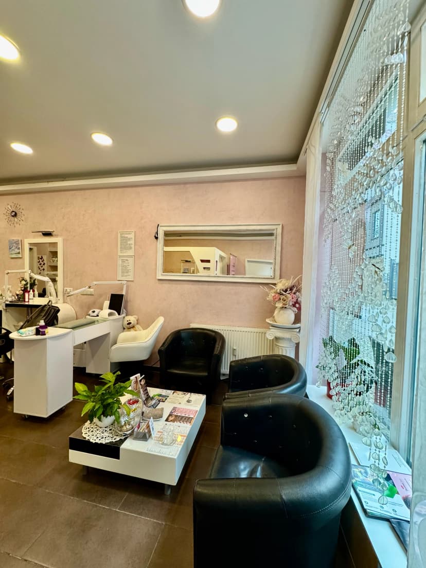 Cozy salon waiting area with comfortable black chairs and decorative elements by the window