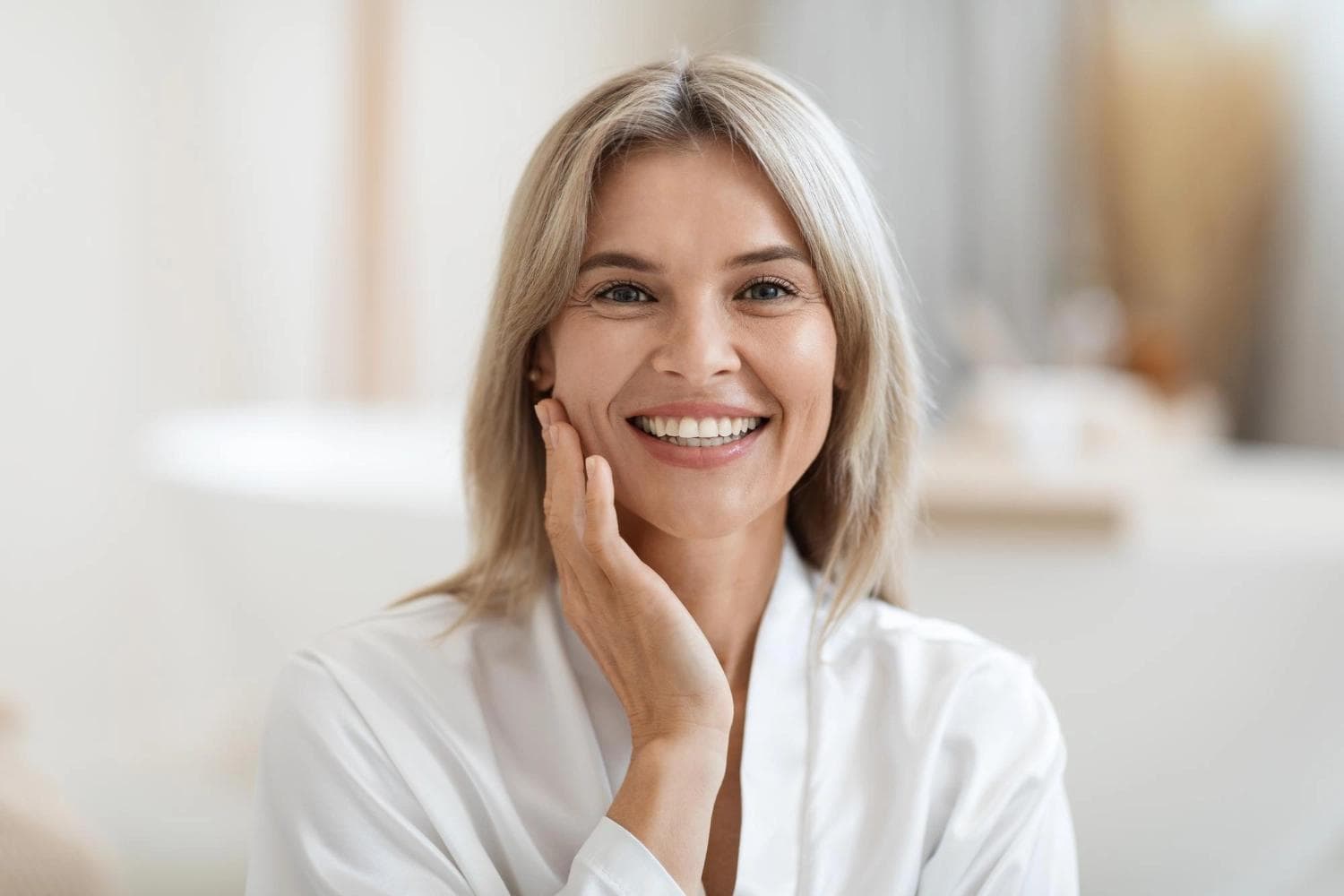 Glückliche Frau mit strahlender Haut berührt sanft ihr Gesicht nach einer SQT Bio Microneedling-Behandlung und zeigt leuchtende und gesunde Ergebnisse nach der Behandlung.
