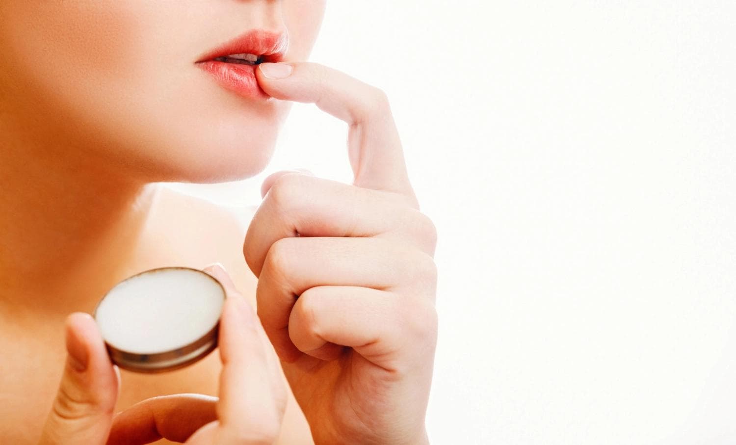 Frau trägt Heilsalbe auf die Lippen auf als Teil der Nachsorge für Permanent-Make-up